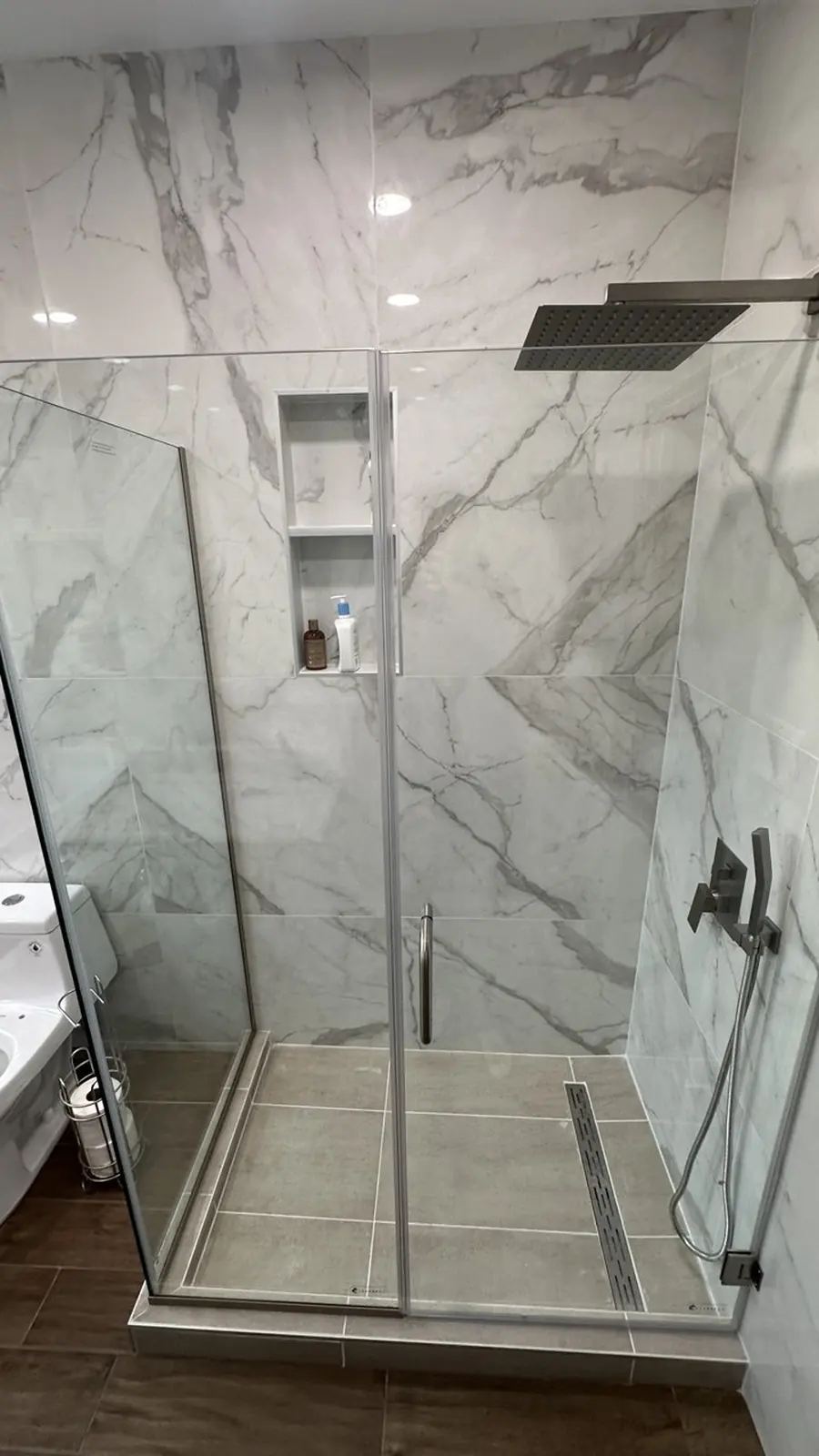 Frameless glass shower in marble-look porcelain — YKCA Bay Area remodel